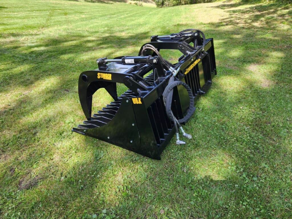 Stinger ROG skid steer rock grapple with dual grapples designed for handling rocks, logs and brush on landscaping jobs