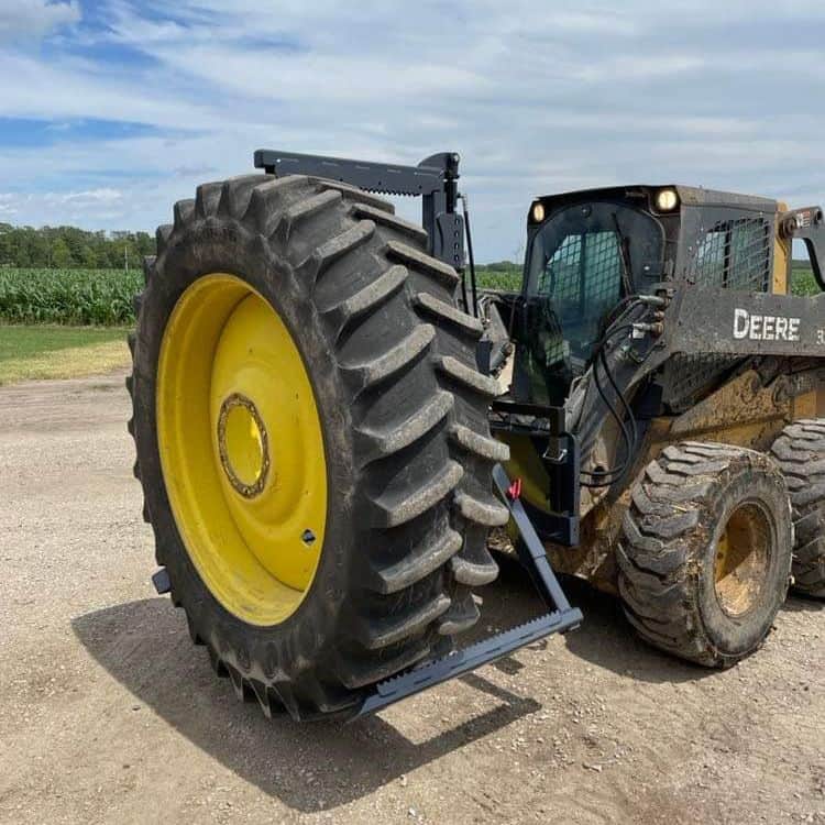 Skid steer loader using ECHO OG tire handler attachment to handle oversized tractor tire