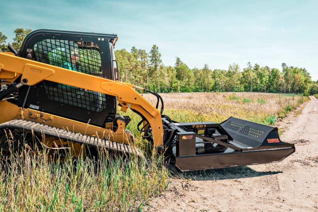 Skid steer running Brush Wolf open front heavy duty brush cutter in field
