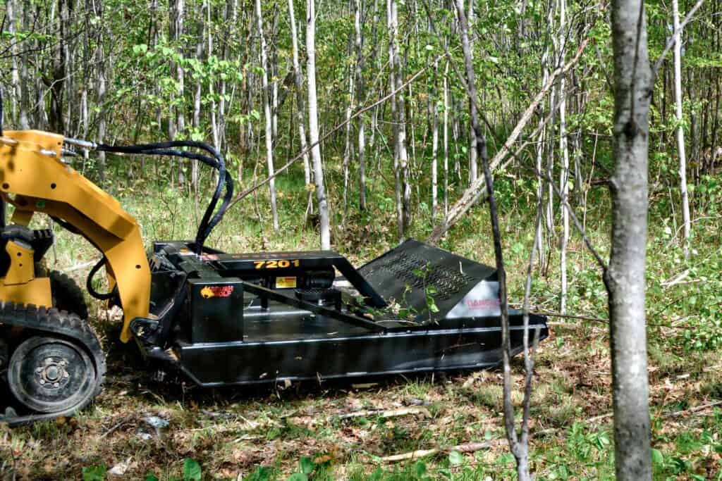 Brush Wolf open front heavy duty skid steer brush cutter clearing brush in wooded area