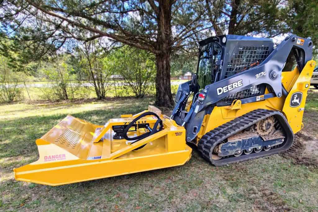 Compact track loader running Brush Wolf heavy duty open front brush cutter clearing forest undergrowth