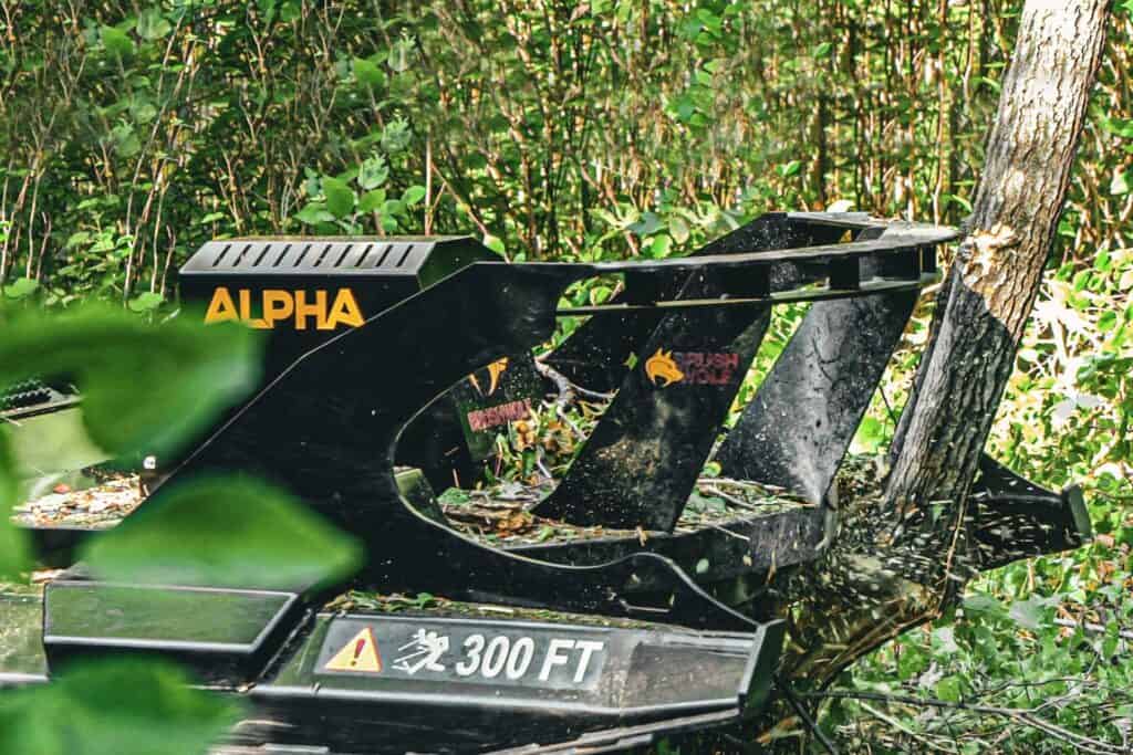 Brush Wolf Alpha Series skid steer brush cutter cutting small trees and dense brush in forest clearing