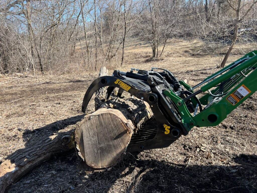 Stinger CROG compact tractor rock grapple attachment grabbing log during forestry work