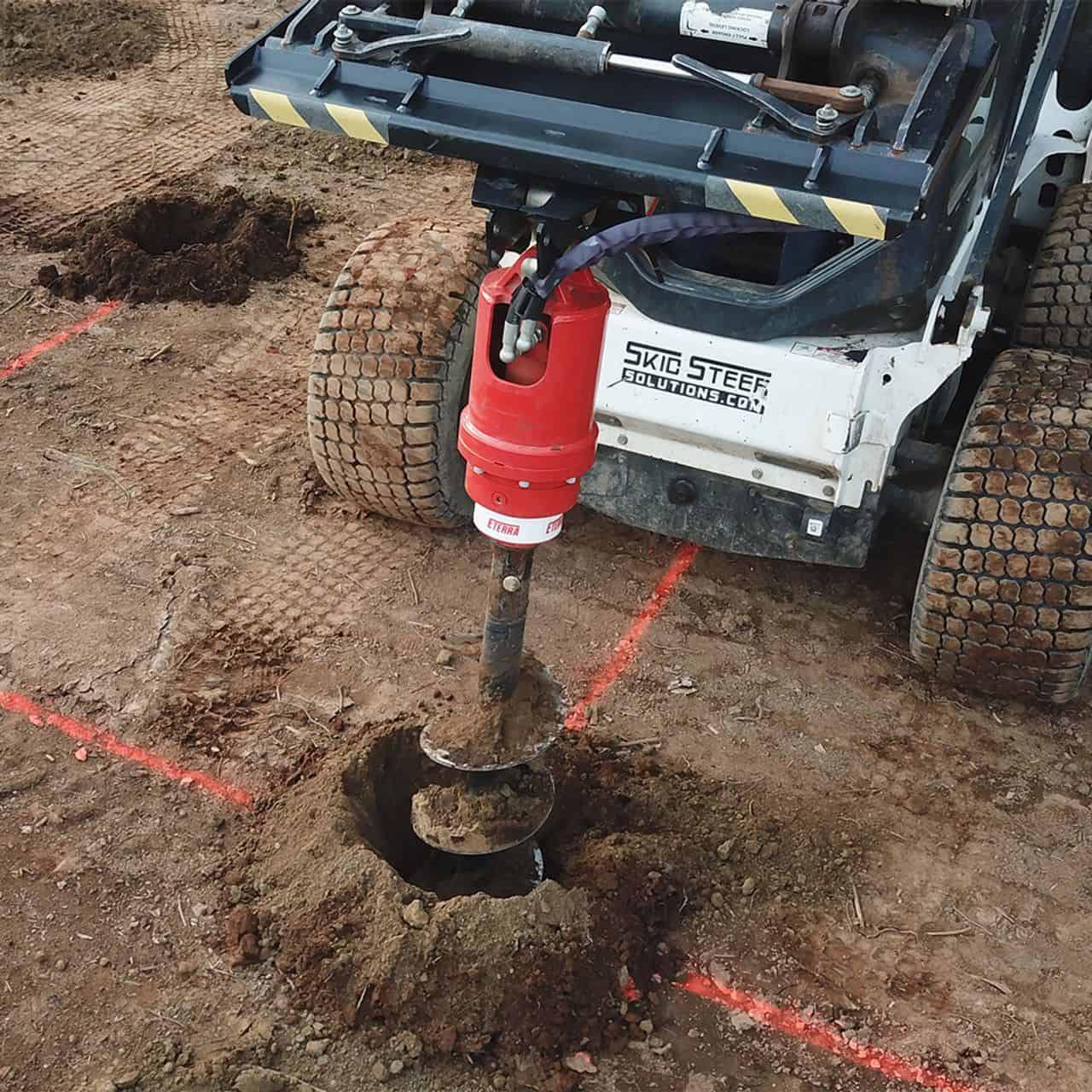 Skid steer auger drive attachment drilling post holes with Eterra auger motor