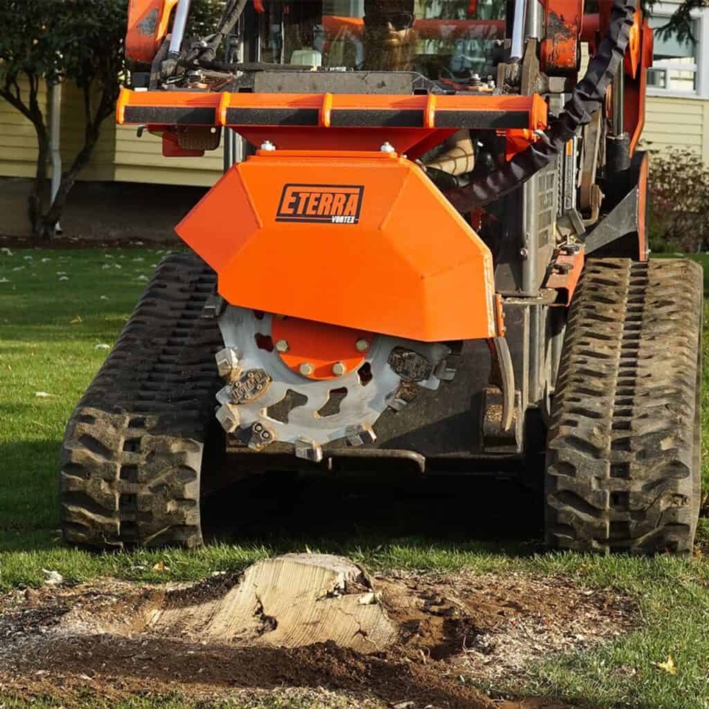 Front view Eterra Vortex skid steer stump grinder attachment mounted on skid steer during stump removal demonstration