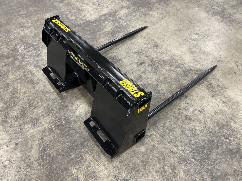 Stinger BS2 skid steer bale spear attachment with dual forged hay bale spears on concrete shop floor