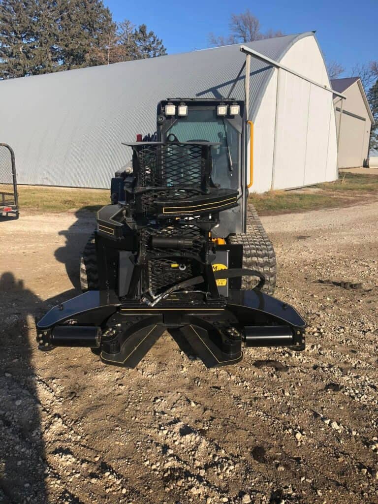 M&M Hydra Clip 16 inch tree shear front view mounted on skid steer near shop building