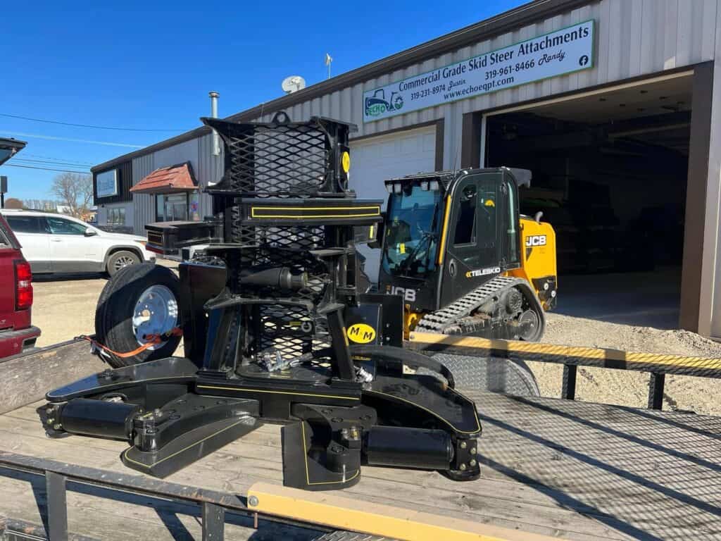 M&M Hydra Clip 16 inch skid steer tree shear attachment loaded on trailer outdoors