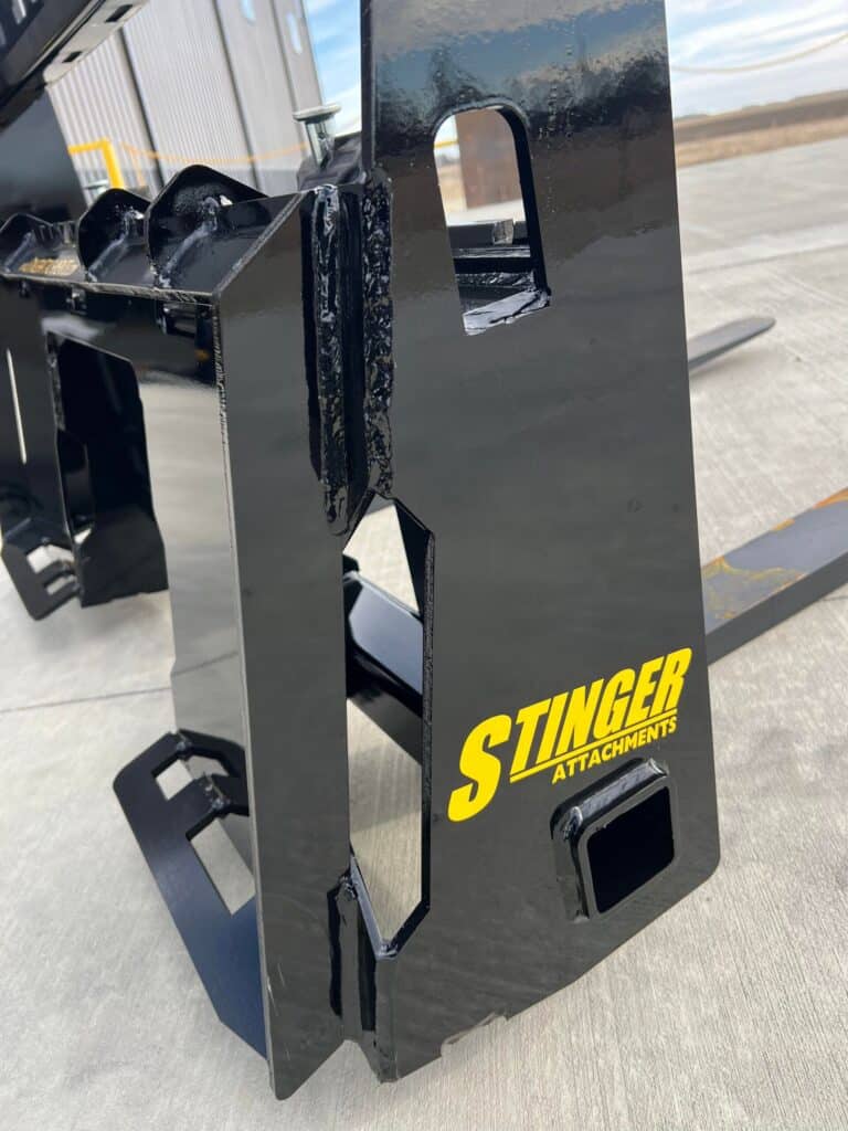 Stinger skid steer pallet forks frame close up showing reinforced carriage, fork mounts, and heavy duty steel construction