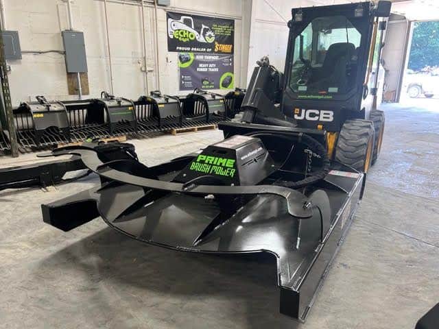 Prime Attachments direct drive skid steer brush mower mounted on loader inside shop showing hydraulic motor and deck