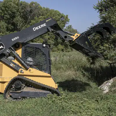 Prime Attachments skid steer rock and brush grapple front view showing dual clamp arms and tine spacing for debris