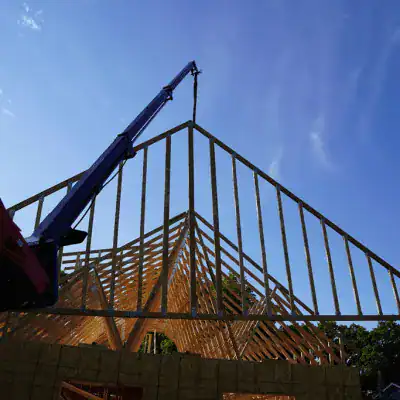 Prime Attachments telescopic boom installing trusses on structure showing high reach lifting for building construction