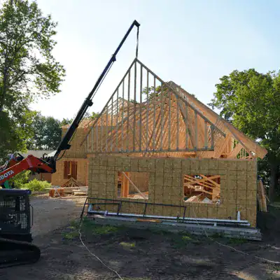 Prime Attachments skid steer telescopic boom lifting roof trusses showing extended reach for framing and construction work