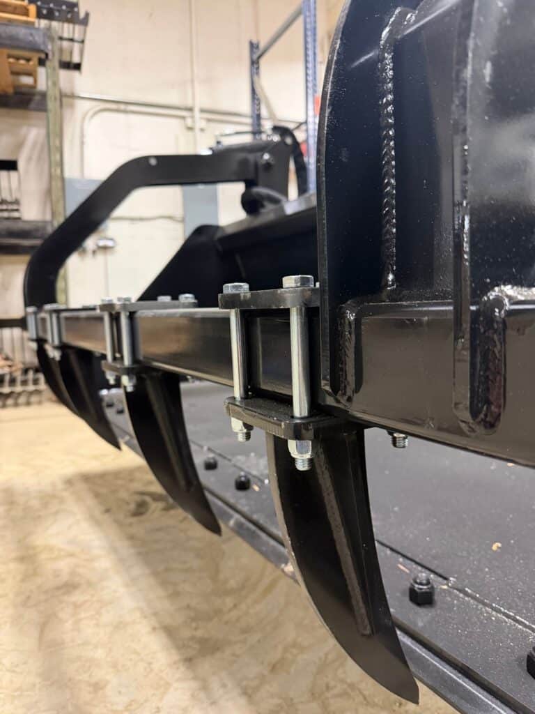 Prime Attachments high capacity skid steer grapple side view showing replaceable wear components and steel frame