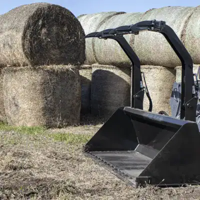 Prime Attachments high capacity skid steer grapple lifting stacked round hay bales in farm environment