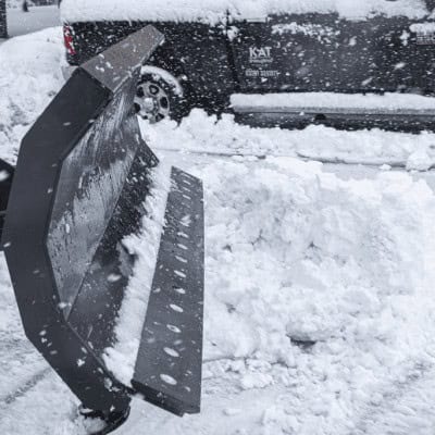 Prime Attachments skid steer snow blade pushing snow beside CAT compact track loader