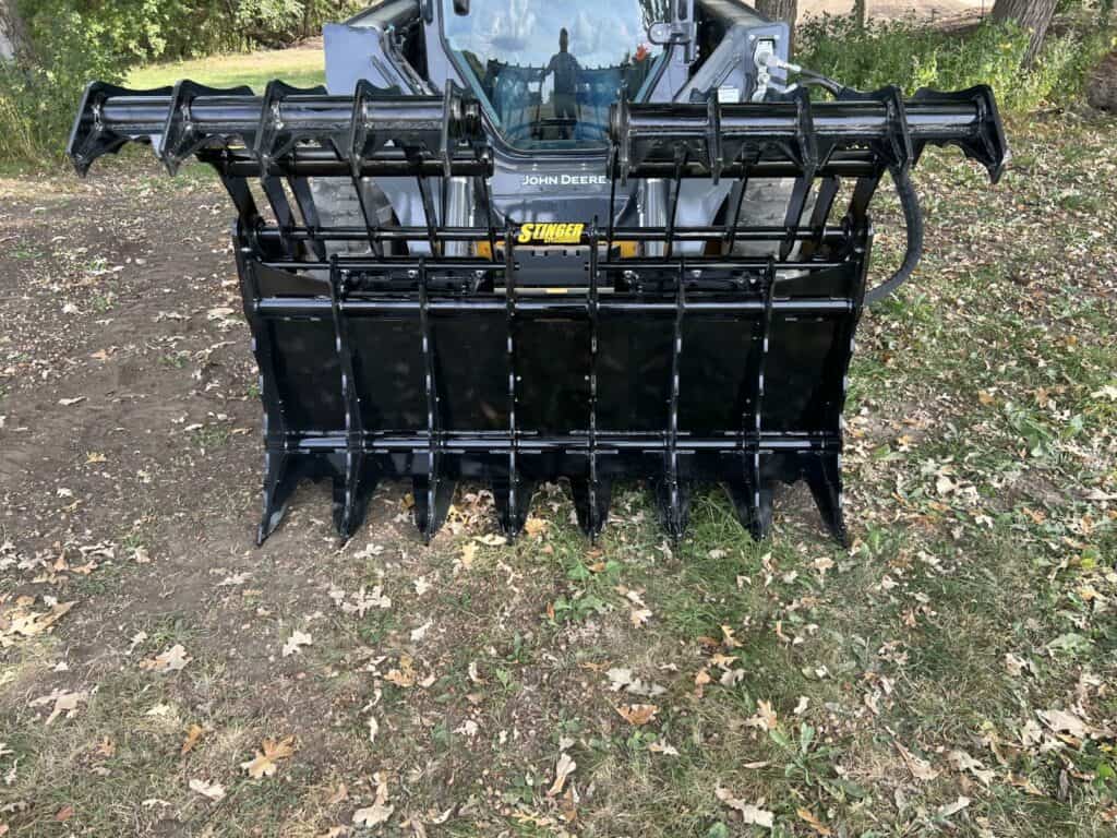 Stinger CC skid steer clam grapple head on view mounted on skid steer showing maximum material capacity and grip width