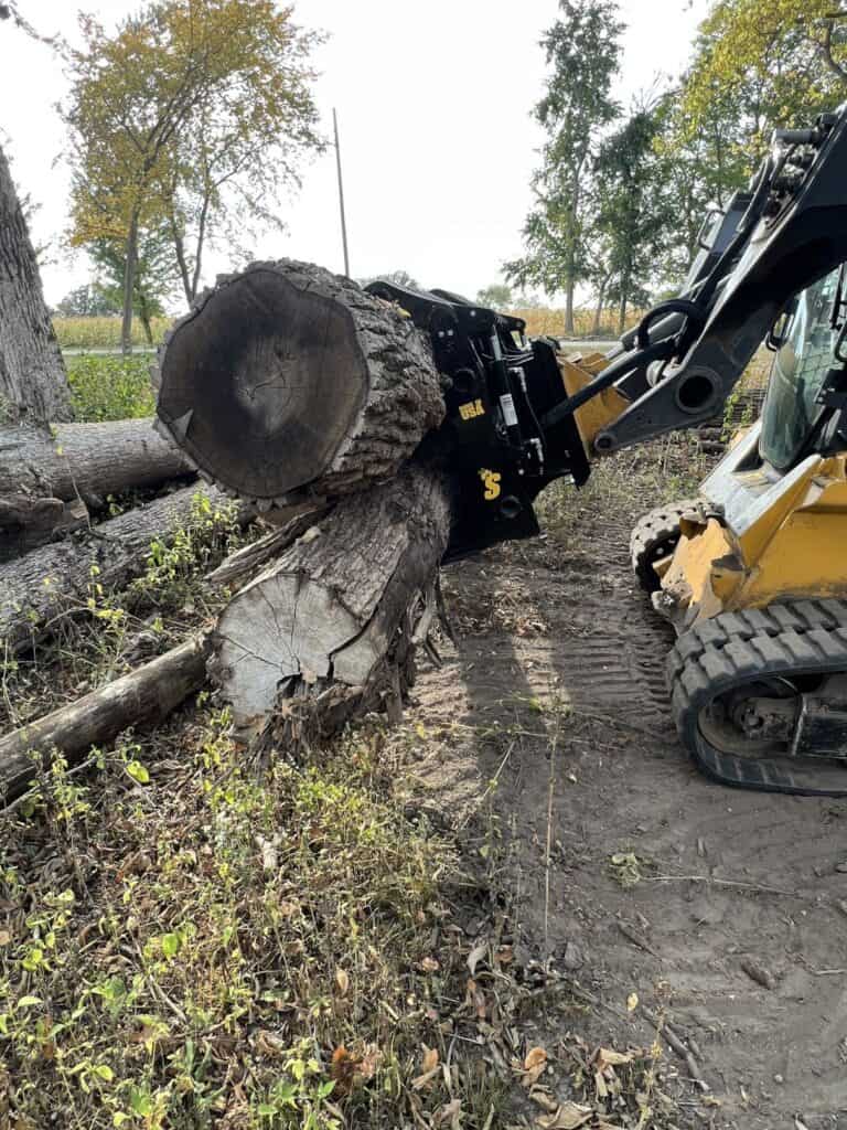 Stinger CC skid steer clam grapple lifting large log showing powerful grip strength and forestry material handling capability