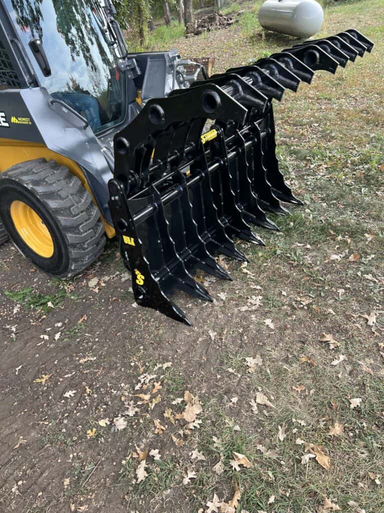 Stinger CC skid steer clam grapple open position showing wide jaw spread and lower tine layout for debris handling