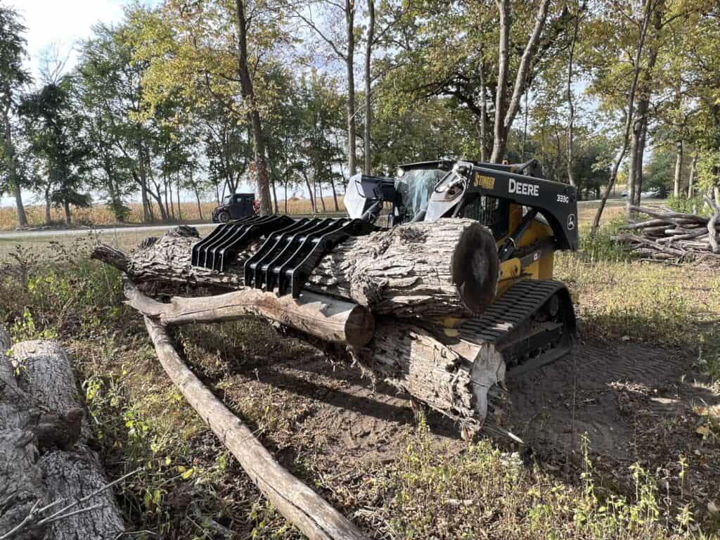 Stinger CC skid steer clam grapple moving soil and debris demonstrating versatility for land clearing and cleanup jobs