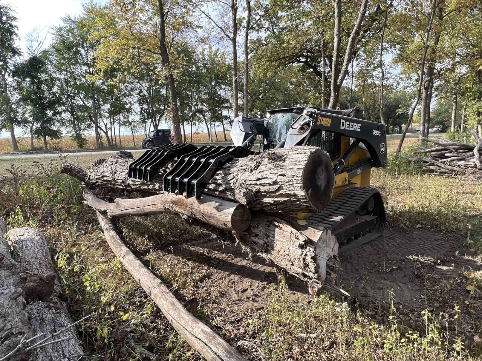 Stinger CC skid steer clam grapple moving soil and debris demonstrating versatility for land clearing and cleanup jobs