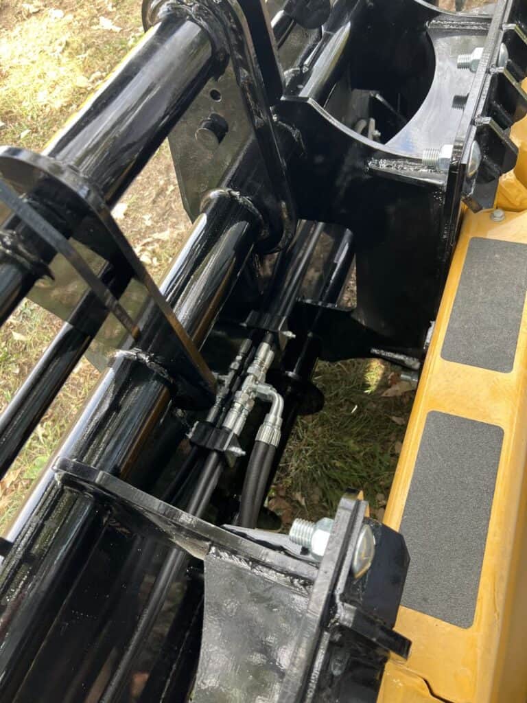 Stinger CC skid steer clam grapple hydraulic cylinder detail showing protected hoses and heavy duty steel construction