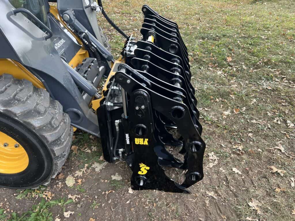 Stinger CC skid steer clam grapple angled view showing dual clamp arms, heavy duty tines, and reinforced grapple frame
