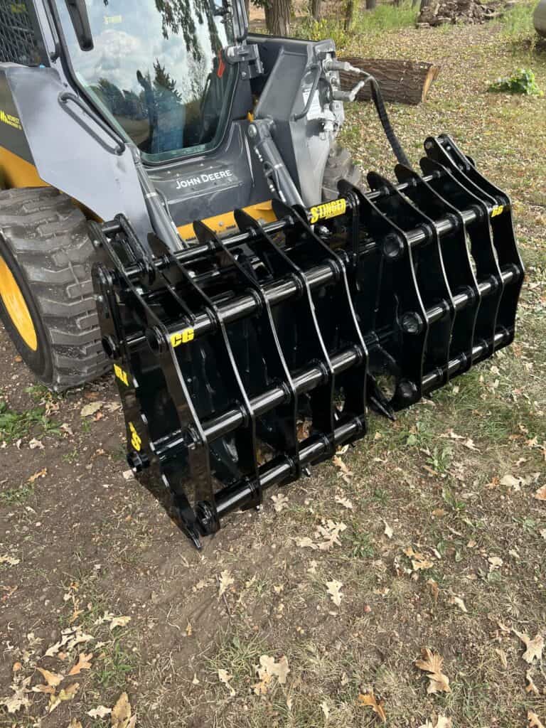 Stinger CC skid steer clam grapple mounted on loader grabbing debris showing wide opening jaws and strong hydraulic clamping