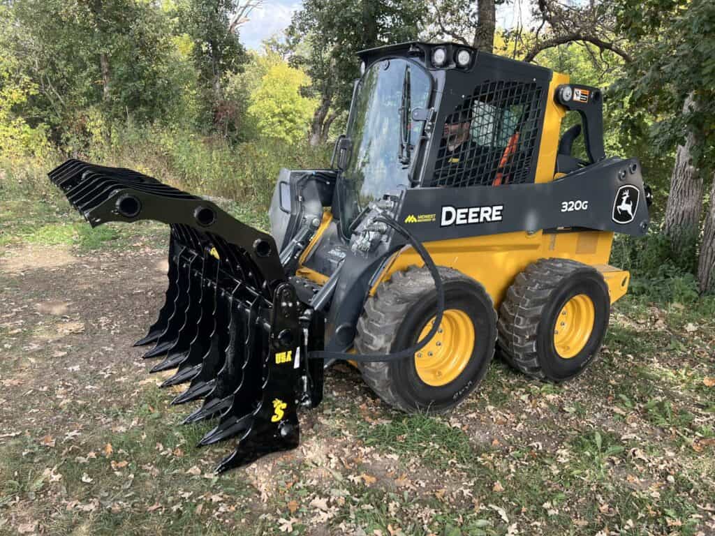 Stinger CC skid steer clam grapple in use clearing logs and brush showing strong clamping force and attachment control