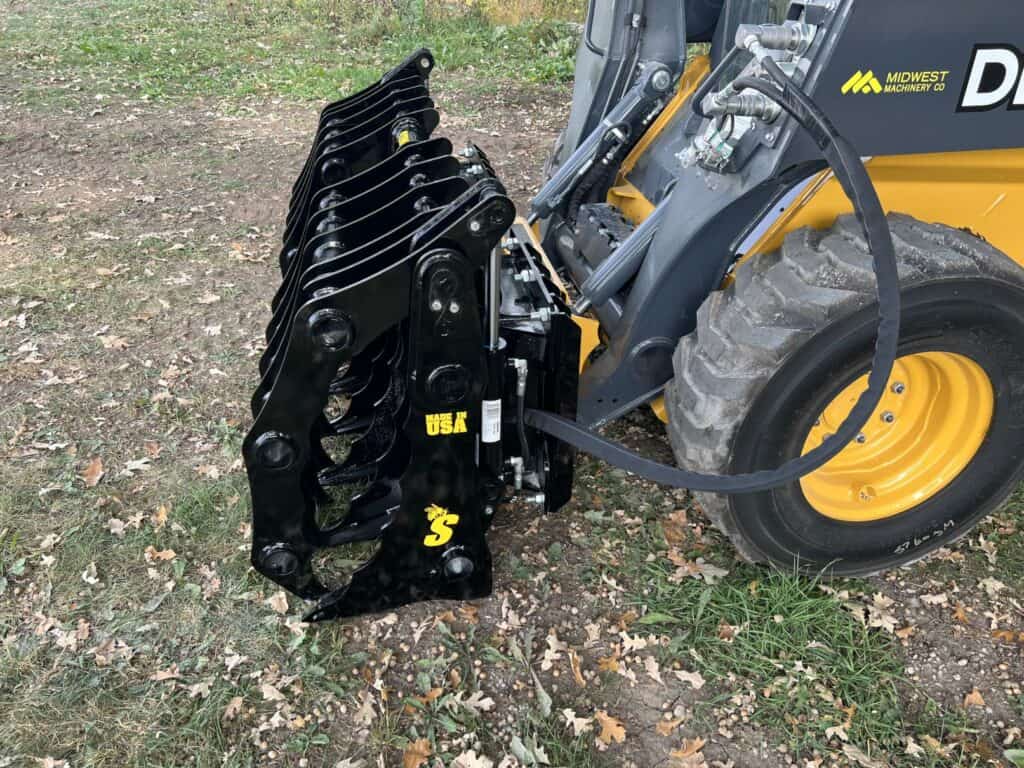 Stinger CC skid steer clam grapple side view attached to skid steer highlighting cylinder placement and compact design
