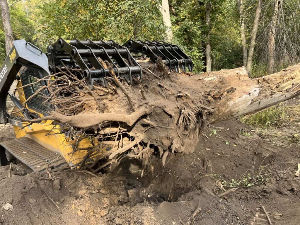 Stinger CC skid steer clam grapple moving stump and debris demonstrating versatility for land clearing and cleanup jobs