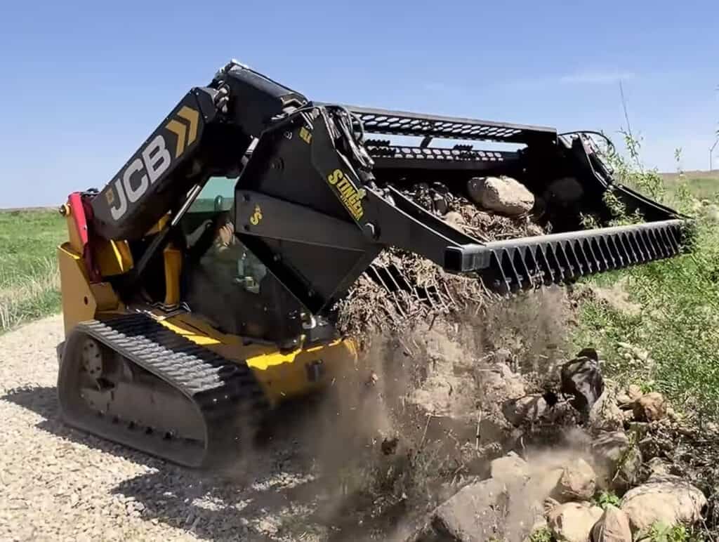 Stinger RK skid steer rock bucket dumping material showing dirt falling through tines while retaining rocks