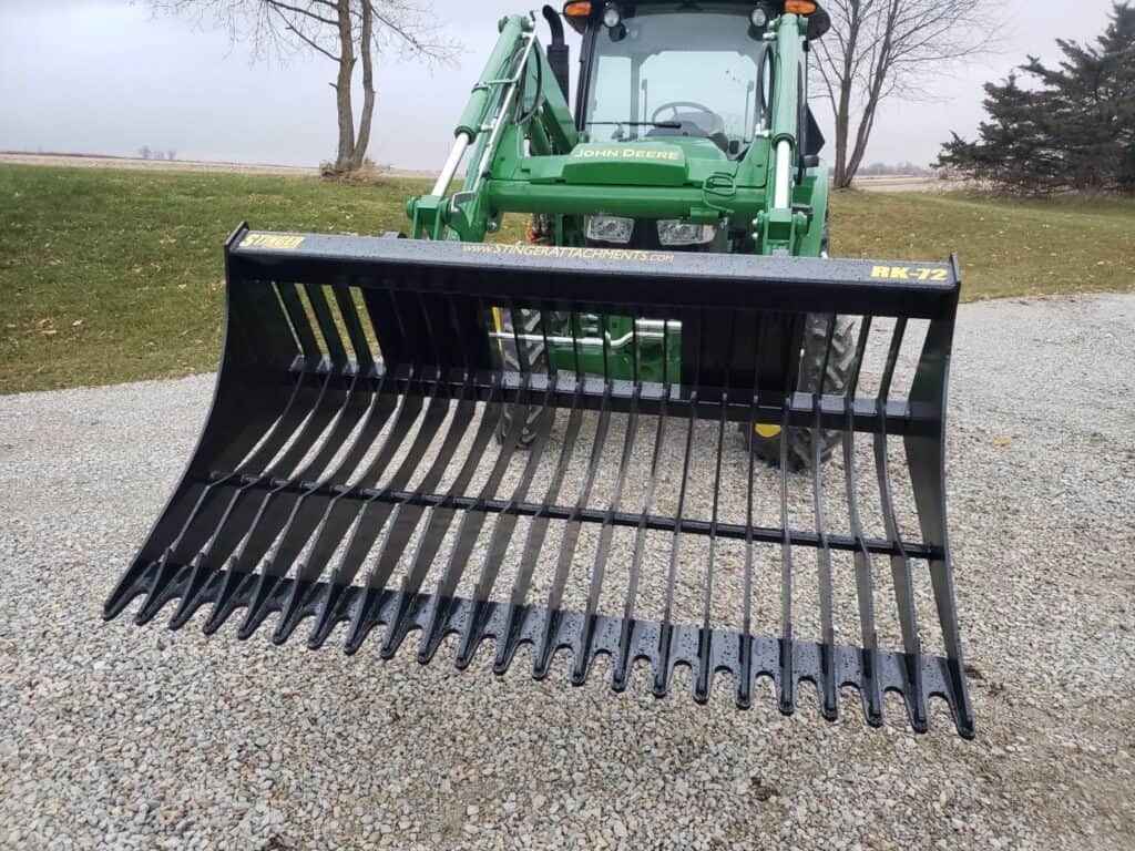 Stinger RK rock bucket mounted on tractor front view showing wide tine spacing for efficient rock and debris separation