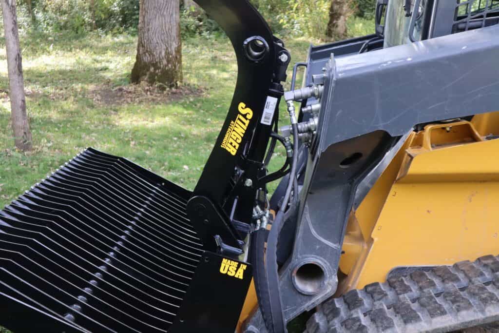 Stinger ROG skid steer rock grapple left side view showing clamp arm and tine design for material handling