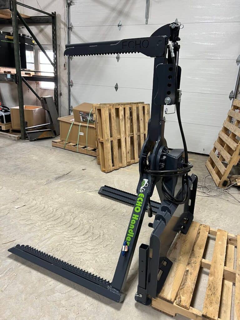 ECHO OG skid steer tire handler attachment mounted inside warehouse with lifting arm extended