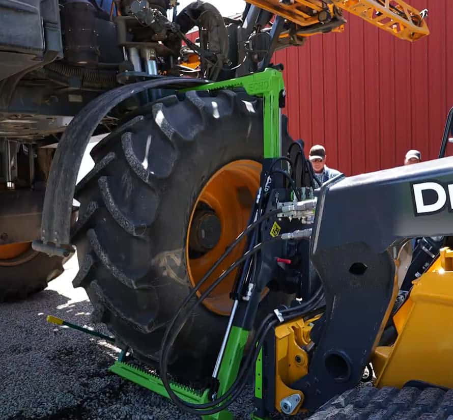 ECHO Handler X3 agricultural tire handler positioned around a large sprayer tire with a compact track loader