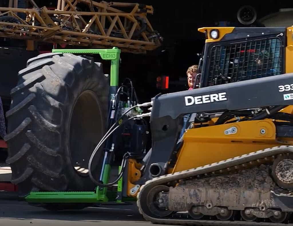 John Deere compact track loader using the ECHO Handler X3 tire handler to position a large agricultural tire