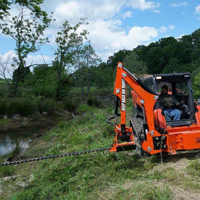 Eterra Raptor boom arm with sickle bar mower trimming brush showing precision cutting along fence lines
