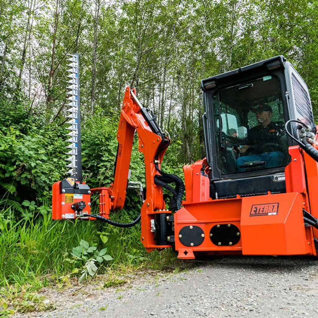 Eterra Raptor skid steer boom mower attachment trimming vegetation and brush along wooded trails