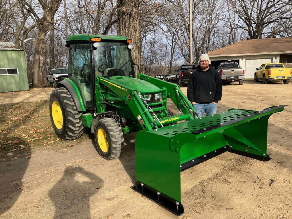 John Deere compact tractor with ECHO CTP compact tractor pusher attachment pushing gravel on property