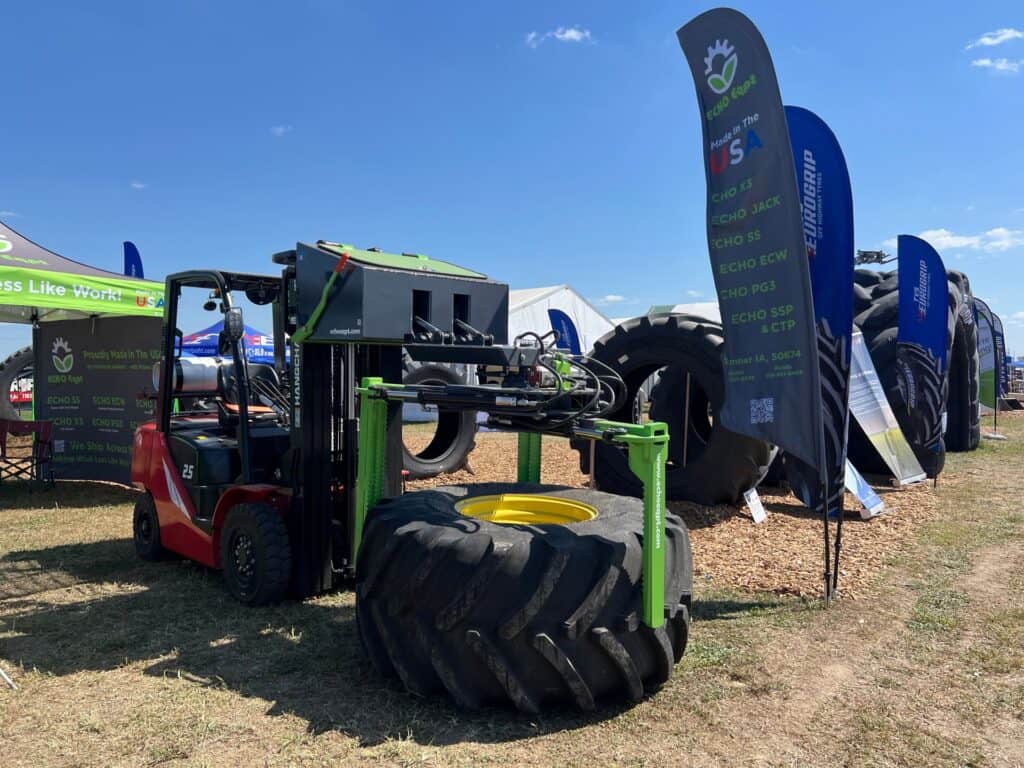 Forklift using ECHO X3FL tire grabber attachment to handle oversized farm tractor tire at equipment trade show