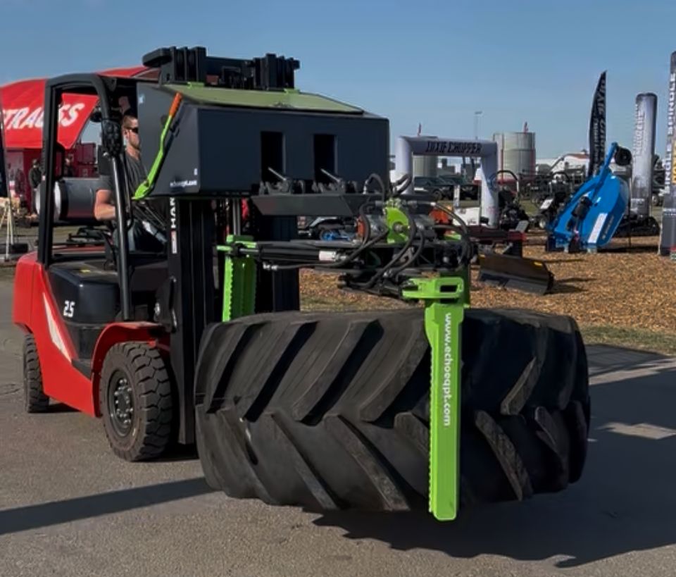 Forklift using ECHO X3FL tire grabber attachment to handle large farm tractor tire at equipment show