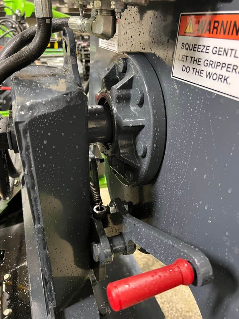 Detail view skid steer tire grabber attachment with hydraulic controls for large tractor tires