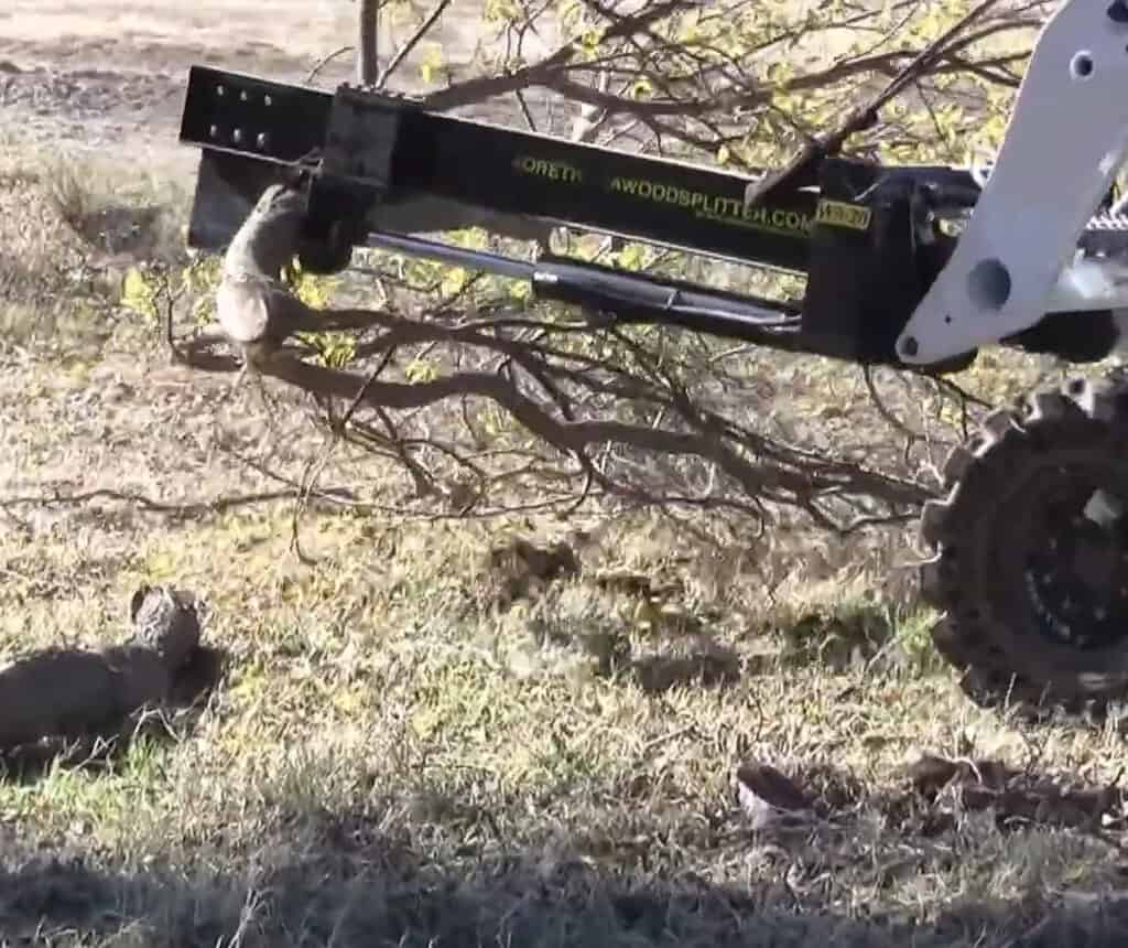 M&M Hydra Split skid steer log splitter splitting branches and wood debris outdoors