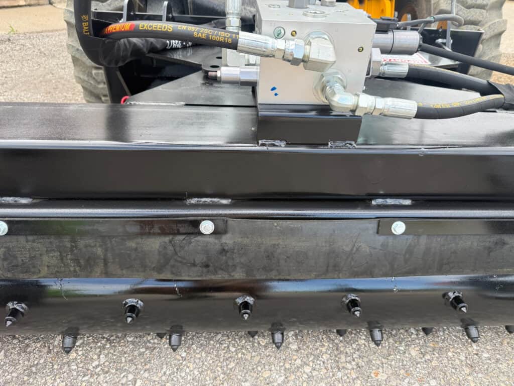 Close-up of PRIME soil conditioner hydraulic valve block, hoses and studded conditioning drum