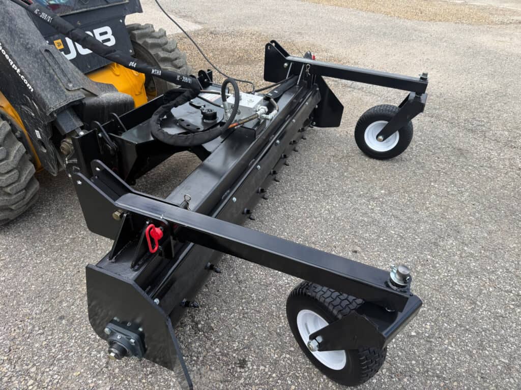 Rear angle view of PRIME soil conditioner for skid steers showing drum, hydraulic lines and support wheels