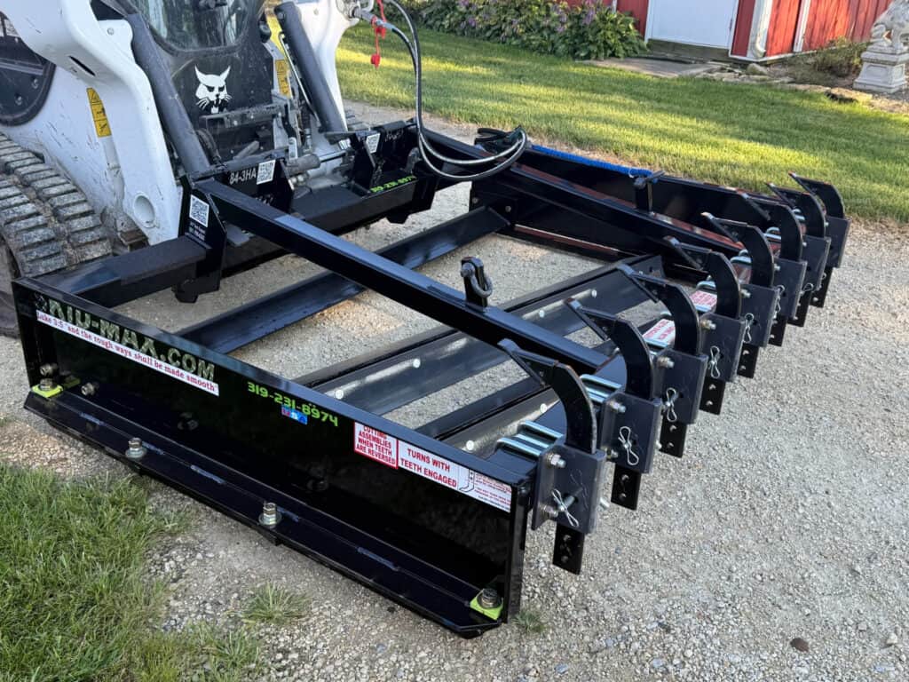 Front view of black Skid Max 3 blade hydraulic skid steer grader on Bobcat loader