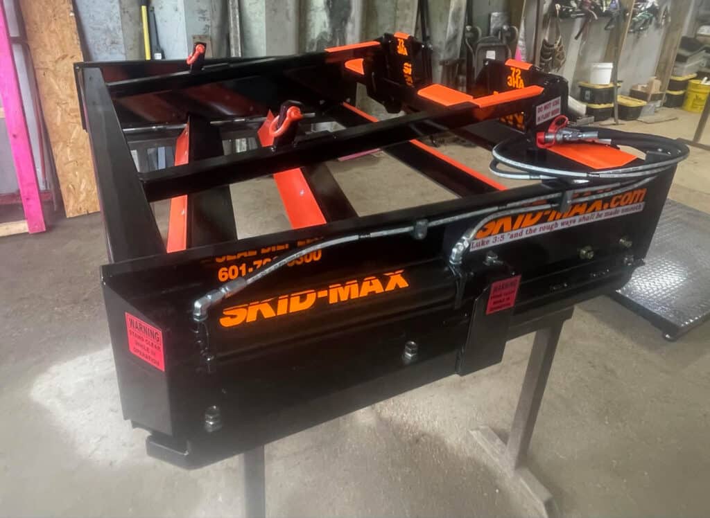 Close up of orange Skid Max 3 blade hydraulic skid steer grader rear frame and branding