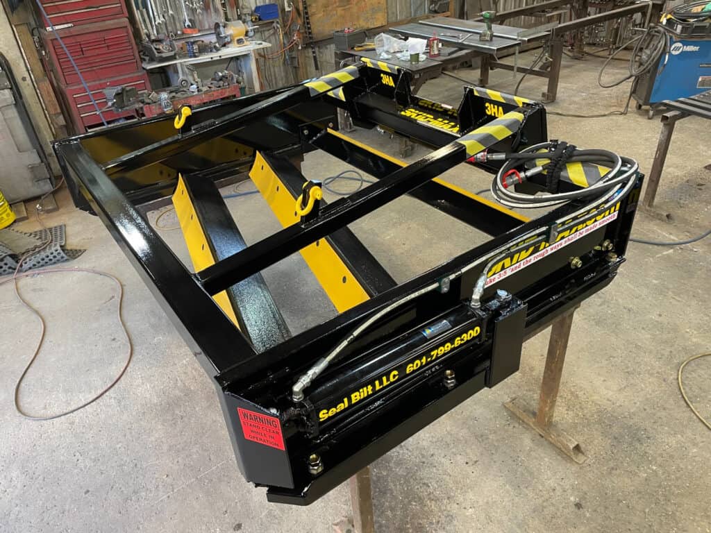 Yellow Skid Max 3 blade hydraulic skid steer grader attachment in workshop