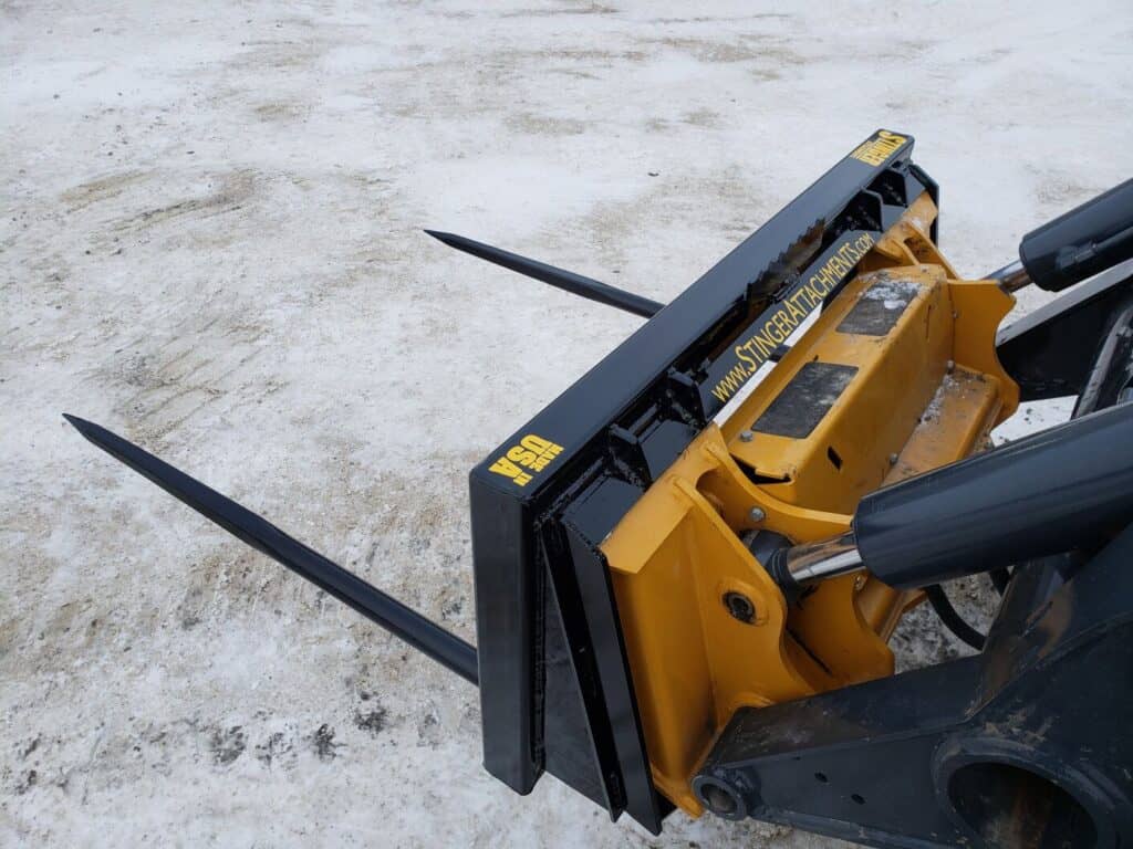 Stinger BS2 skid steer bale spear front view on machine showing spear spacing and attachment positioning